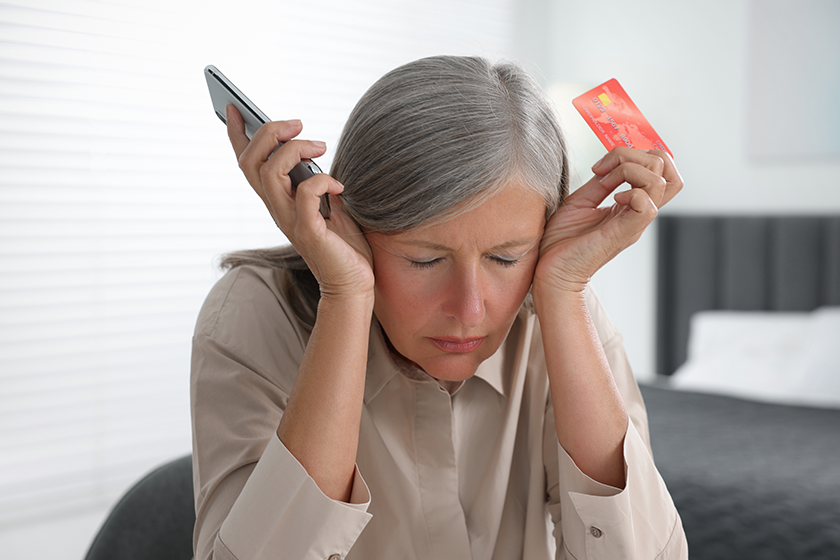 Scammed woman with credit card and smartphone indoors. Be careful - fraud 